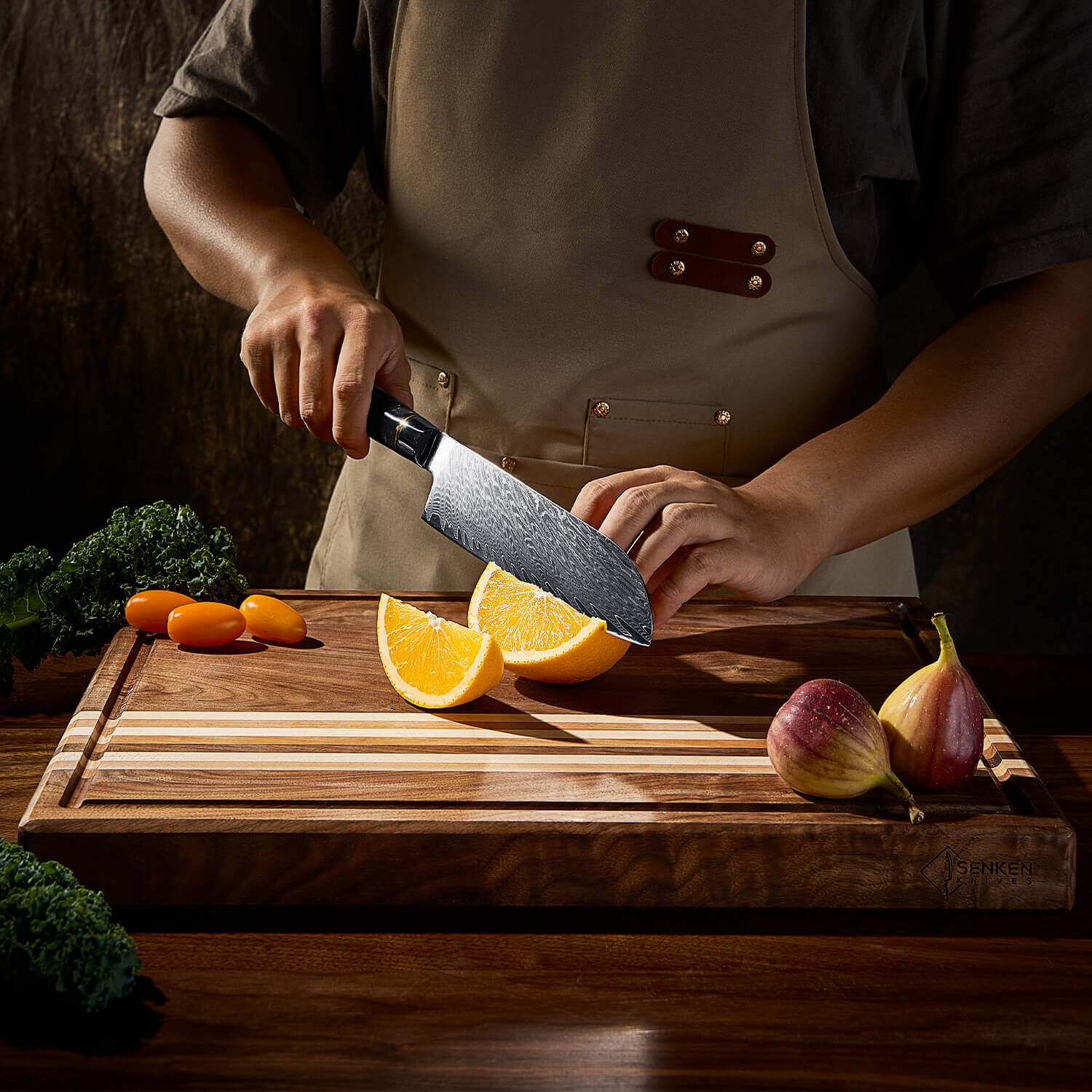 Person cutting an orange on a wooden cutting board with various fruits and vegetables around.