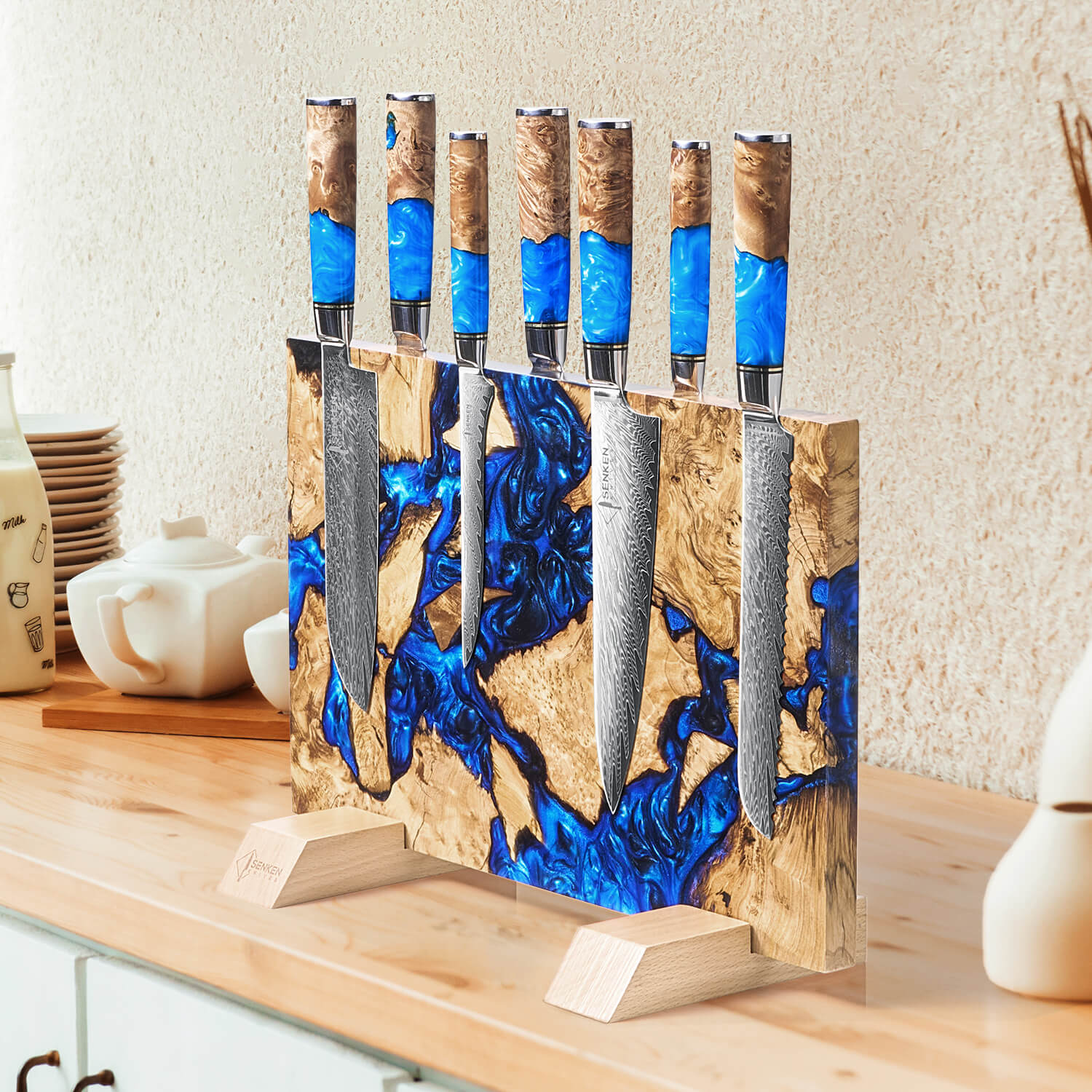 Set of knives with blue handles in a wooden stand on a kitchen counter.