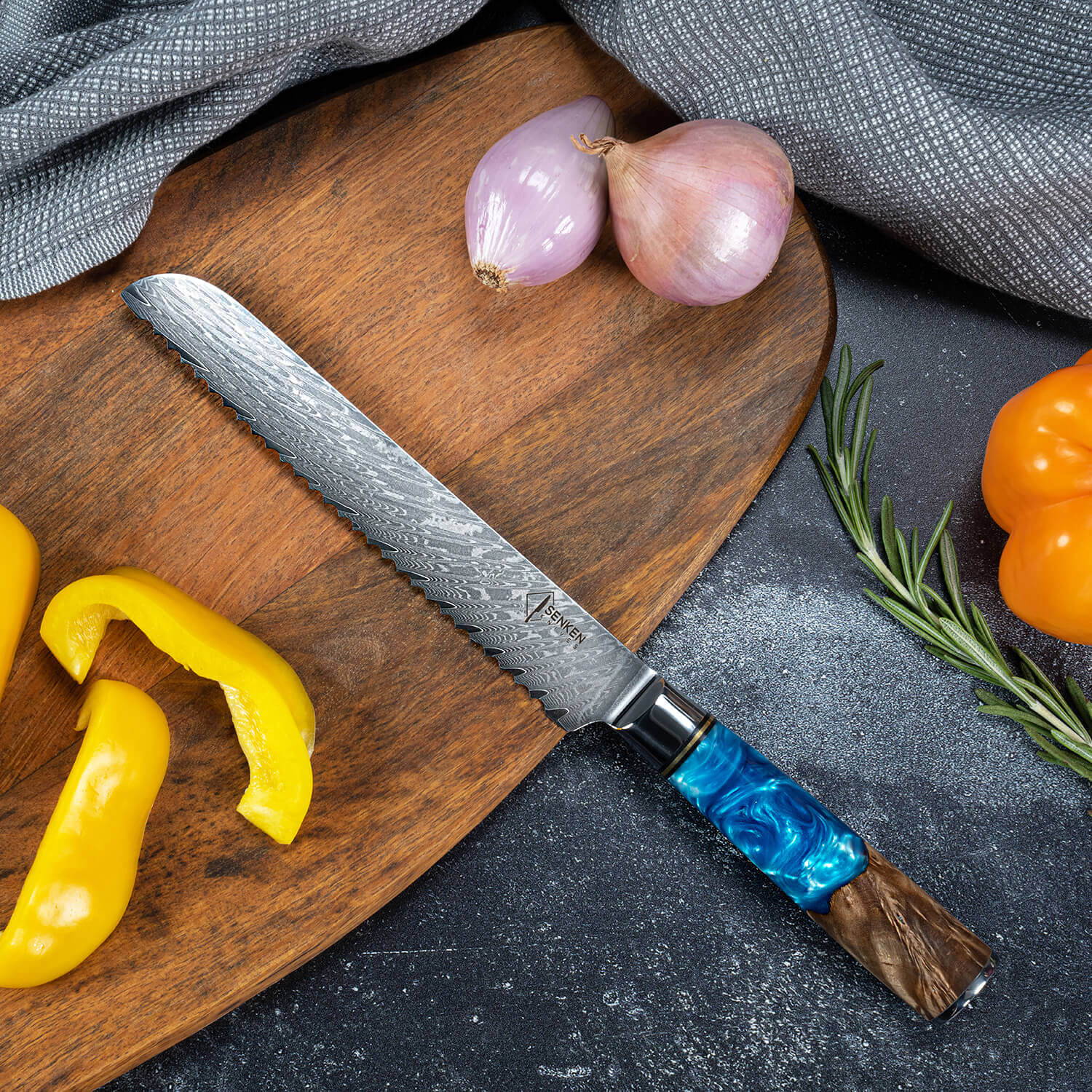 Tsunami Damascus Steel Bread Knife with Blue Resin Wood Handle Cutting on Cutting Board Onions Shallots Pepper