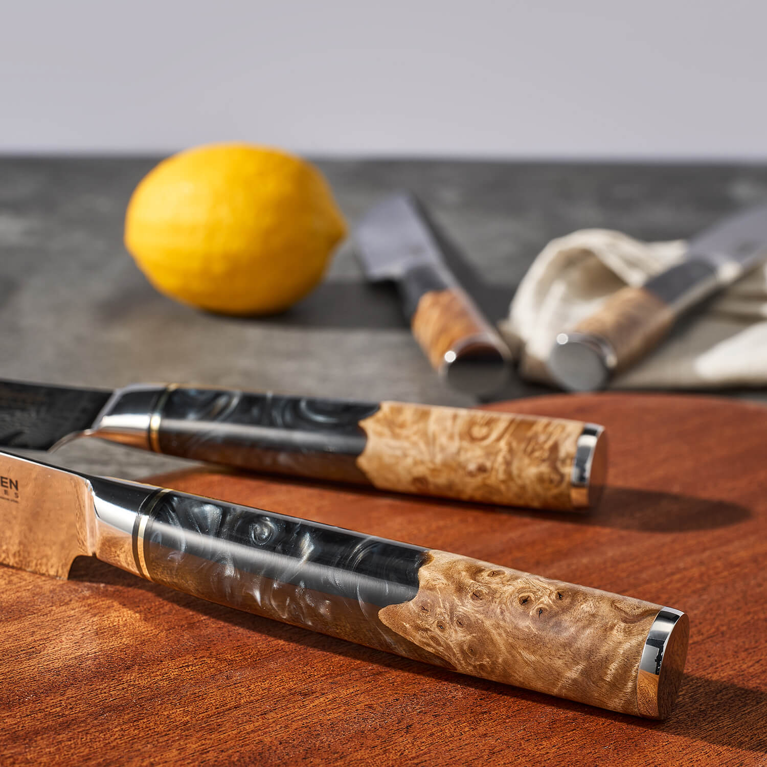 Knives with wooden handles on a wooden surface with a lemon in the background