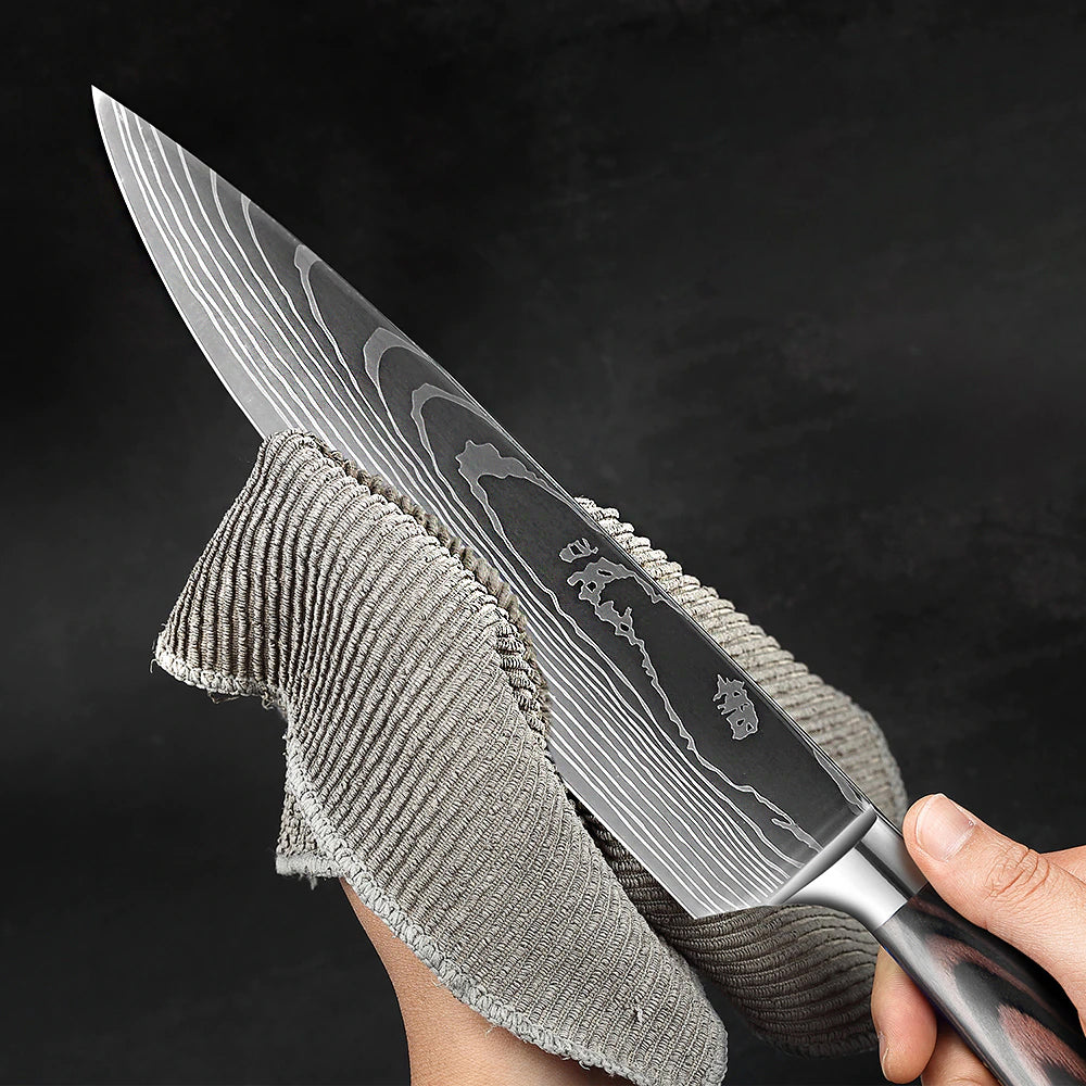 A close-up of a chef's knife with a Damascus steel pattern blade, held by a hand wrapped in a gray cloth against a dark background.