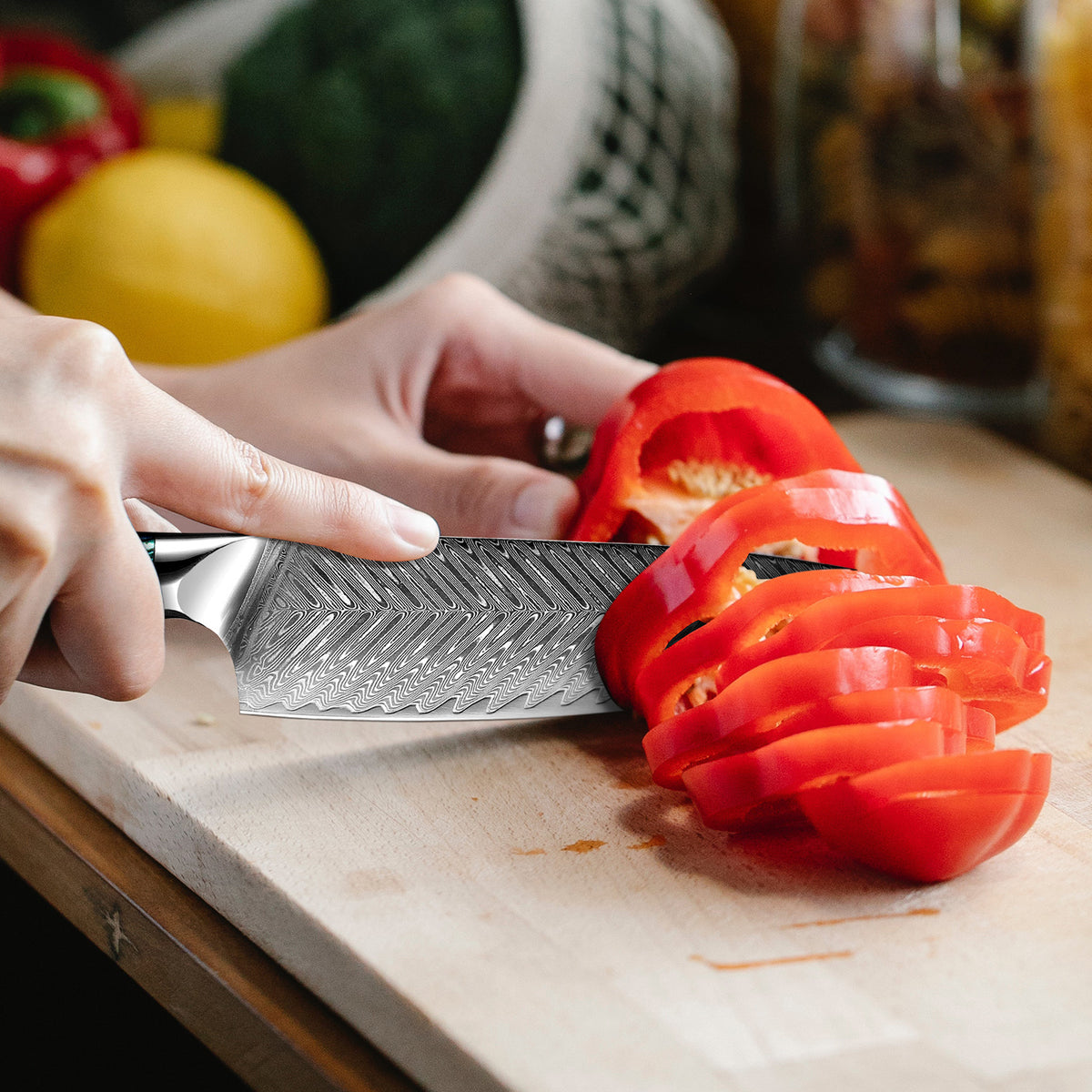 Person slicing a red bell pepper on a cutting board with a knife.